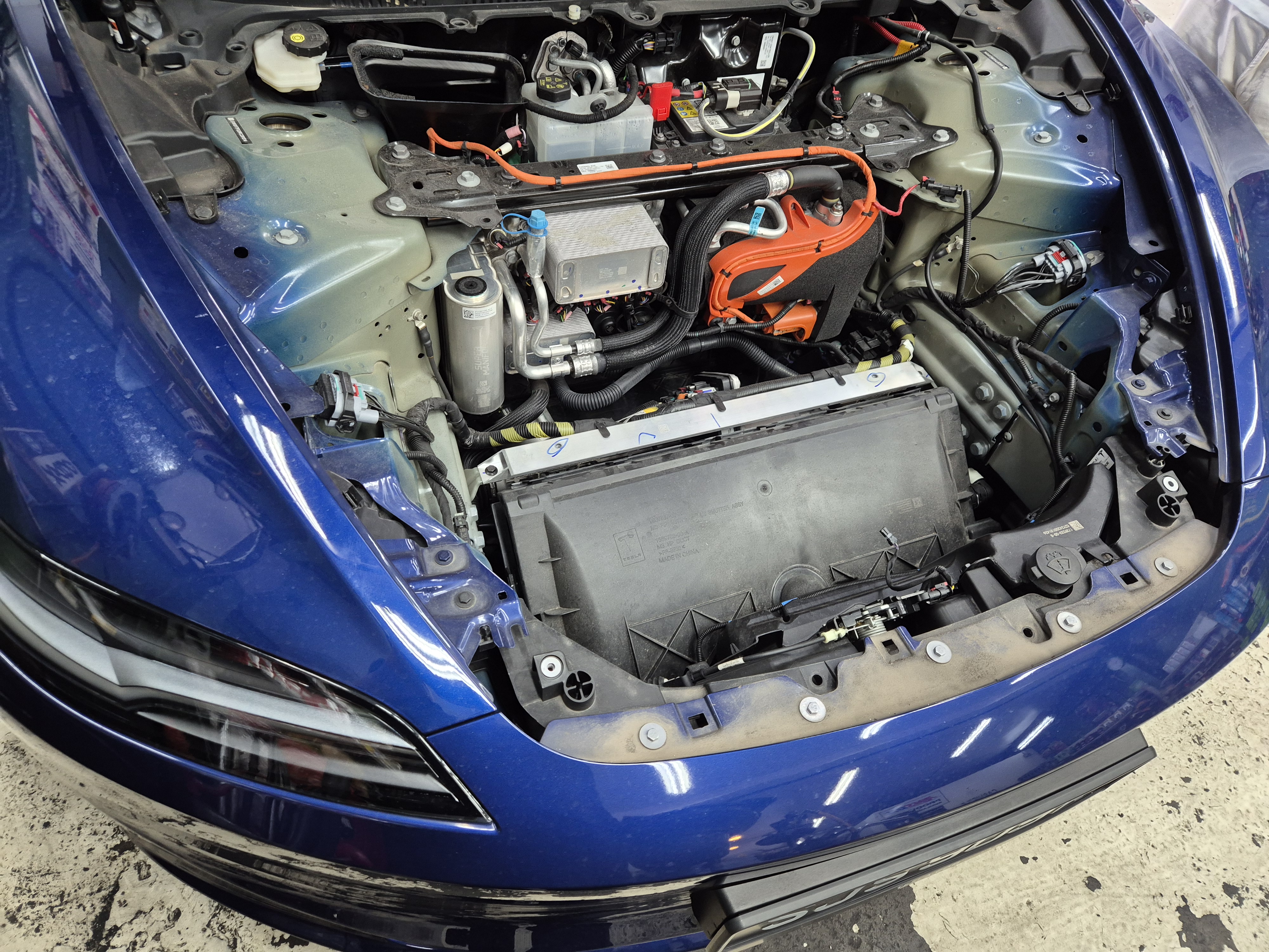 Tesla frunk open showing EV components during servicing