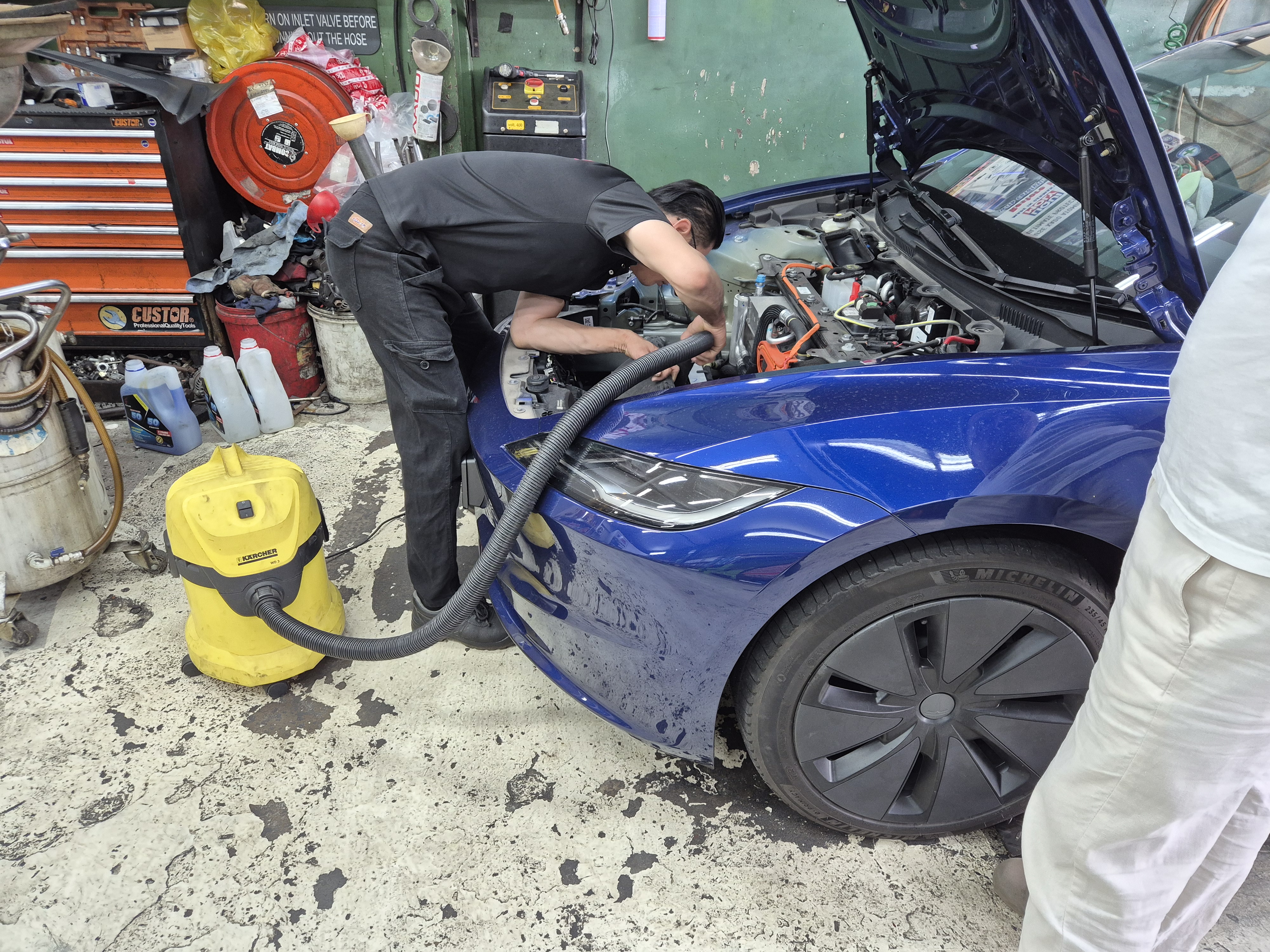 Mechanic using Kärcher vacuum to clean Tesla frunk leaf debris